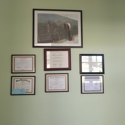 a framed picture and framed diplomas/certifications on a wall